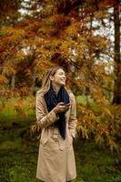 Beautiful young woman using mobile phone in autumn park