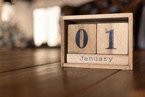 Cube shape calendar for January 01 on wooden surface. Wooden bricks calendar with engraved date 01 January standing on a desk.