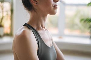 Crop photo of Young fit woman practice yoga doing asana in light yoga studio with green house plant