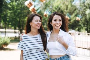 Young women with long hair friends having fun at amusement park photo