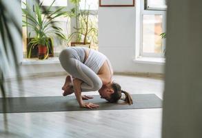 mujer joven en forma practica yoga haciendo asana en estudio de yoga ligero con plantas de casa verde foto