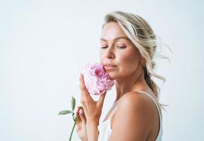 Beauty portrait of blonde hair smiling young woman with pink peony in hand isolated on white background photo