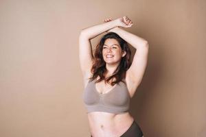 Portrait of self loving woman plus size in underwear on beige background, body love photo