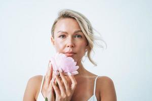 Beauty portrait of blonde hair smiling young woman with pink peony in hand isolated on white background photo