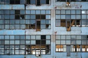 Broken glass facade old, industrial, abandoned factory building. photo