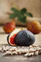 Ripe organic figs on the table. Group of purple and green figs on a farm wooden table with burlap cloth photo