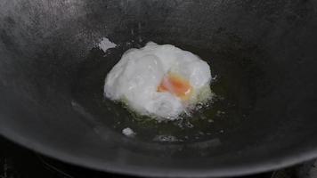 comment faire frire un œuf au plat dans une poêle avec de l'huile chaude et tourner l'omelette d'avant en arrière avec une spatule. video