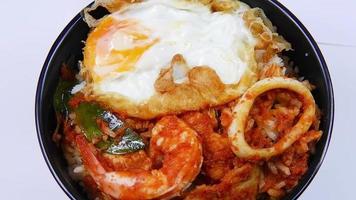 Thai food, fried rice with chili paste, shrimp, pork, squid and fried egg on a black bowl video