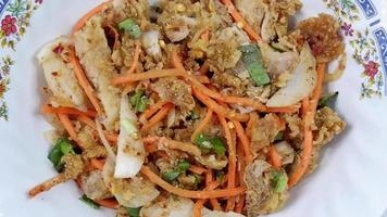 dichtbij omhoog Thais straat voedsel pittig gebakken kip salade met wortels en groenten, wit achtergrond video