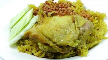 cuisine thaïlandaise traditionnelle poulet biryani grains de riz jaune d'herbes et poulet mariné avec des épices jusqu'à ce qu'il soit parfumé il y a des concombres et des échalotes frites comme plat d'accompagnement. video