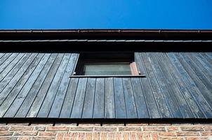 Bottom view of the houses, on the second floor there is a window, against the blue sky, on a sunny day. photo