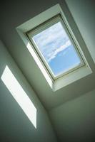 Closed roof window through which you can see the blue sky and white clouds on a sunny day. Bottom view. photo