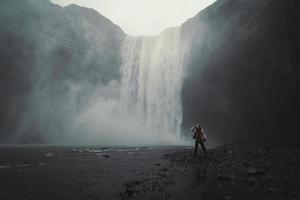 mujer cerca de la foto del paisaje de la cascada de skogafoss