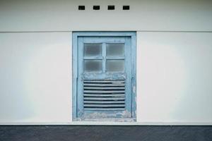 Vintage wooden window with blue paint on white wall photo