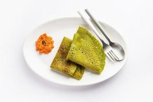 Palak dosa made using mixing spinach or keerai in batter, served with red chutney photo