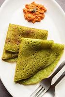 Palak dosa made using mixing spinach or keerai in batter, served with red chutney photo
