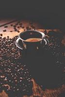 South Indian Filter coffee served in a traditional tumbler or cup over roasted raw beans photo