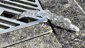 jet of water flows from the iron grille on the pavement in 4k video