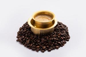 South Indian Filter coffee served in a traditional tumbler or cup over roasted raw beans photo