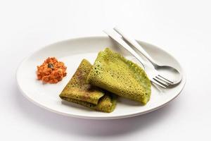 Palak dosa made using mixing spinach or keerai in batter, served with red chutney photo