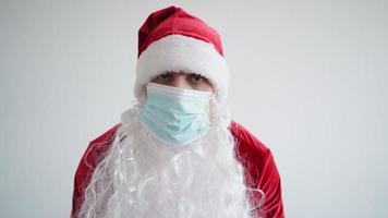 de kerstman claus in een medisch masker looks Bij de camera met een echt kijken Aan een wit achtergrond. Kerstmis quarantaine en coronavirus concept. nieuw jaar pandemie. video