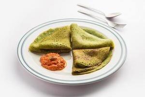 Palak dosa made using mixing spinach or keerai in batter, served with red chutney photo