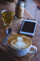 café bebida caliente capuchino arte con leche en una mesa vintage de madera, tiempo de café en un café de fondo de madera foto