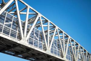 puente blanco con vigas de metal atornilladas sobre fondo de cielo azul. foto