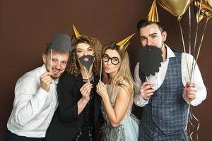 Happy people wearing party hats with photo booth props are celebrating holiday or event