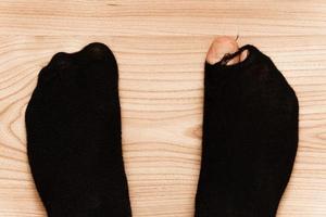 Closeup shot of male feet in hoaly socks with sticking out toe. photo