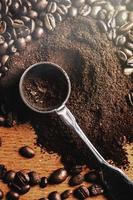 Closeup of steel spoon, grounded coffee and beans photo