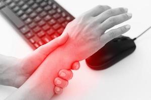 Woman working in office with a carpal tunnel syndrome or wrist joint inflammation photo