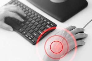 Woman working in office with a carpal tunnel syndrome or wrist joint inflammation photo