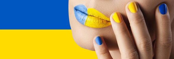 labios femeninos con lápiz labial amarillo y azul y bandera ucraniana en el fondo foto