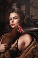 Gorgeous woman with beautiful makeup and hairstyle holding hen photo