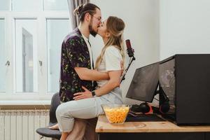 pareja joven besándose en la mesa con computadora personal de juego foto