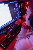 Woman blogger using condenser microphone during online podcast in room with neon light photo