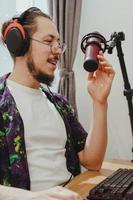 Young man blogger using headphones and condenser microphone  during online podcast stream photo