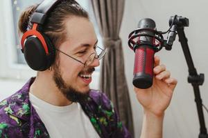 joven blogger usando auriculares y micrófono de condensador durante la transmisión de podcast en línea foto