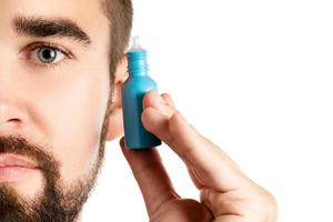 Handsome man holding a small bottle of eyedrops photo