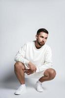 Handsome man wearing white sweatshirt and shorts with wireless earbuds sitting photo