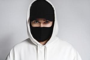 hombre con capucha blanca, gorra de béisbol negra y mascarilla de tela foto