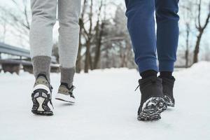 dos pies de corredores durante el jogging de invierno en el parque de la ciudad nevada foto