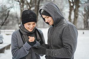 pareja atlética está usando un teléfono inteligente durante el entrenamiento de invierno en el parque de la ciudad nevada foto