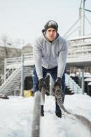 Athlete working out with a battle ropes during snowy winter day photo