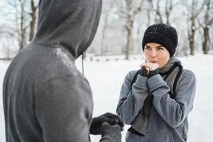 Athletic couple talking in a snowy city park after winter jogging workout photo