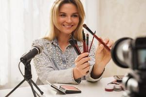 Beauty blogger with  make-up brushes recording video for her followers photo