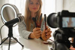 Beauty blogger making a video review of different  make-up brushes for her followers photo