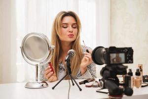 mujer bloguera de belleza aplicándose lápiz labial en los labios durante la grabación de video para sus seguidores foto