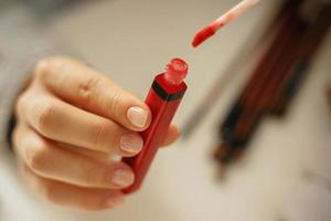 Female hands with tube of red lipstick photo